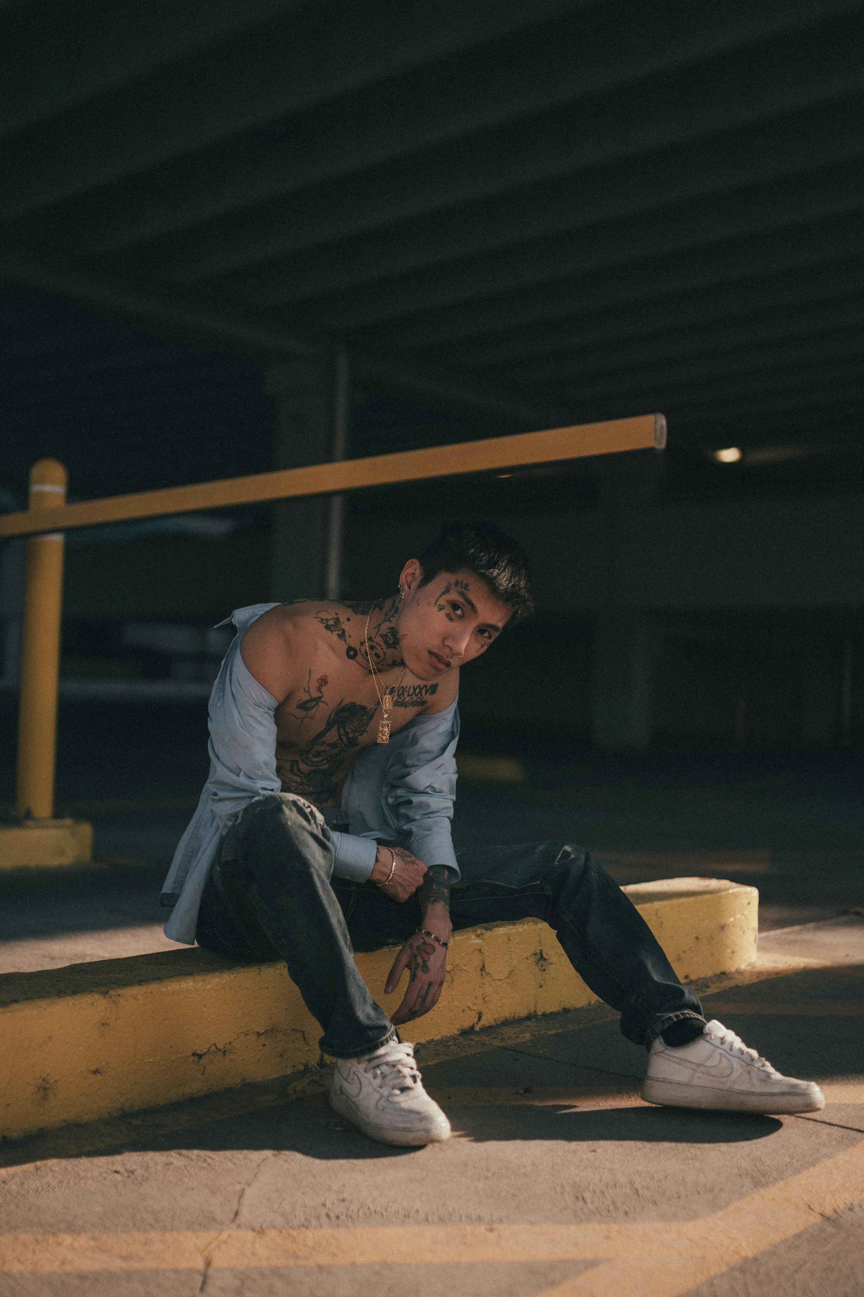 man in white t-shirt and blue denim jeans sitting on brown wooden bench